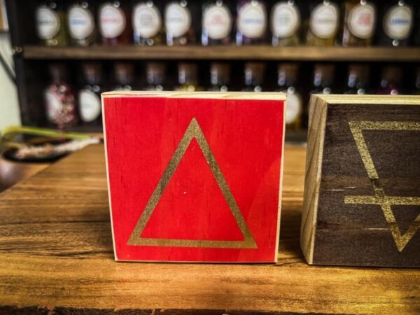 A red triangle sign sitting on top of a wooden table.