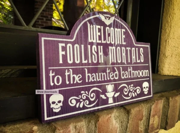 A sign that says " welcome foolish mortals to the haunted bathroom ".