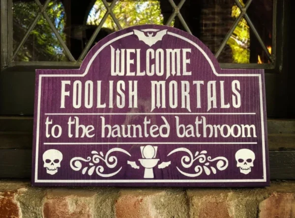 A sign that says welcome foolish mortals to the haunted bathroom.