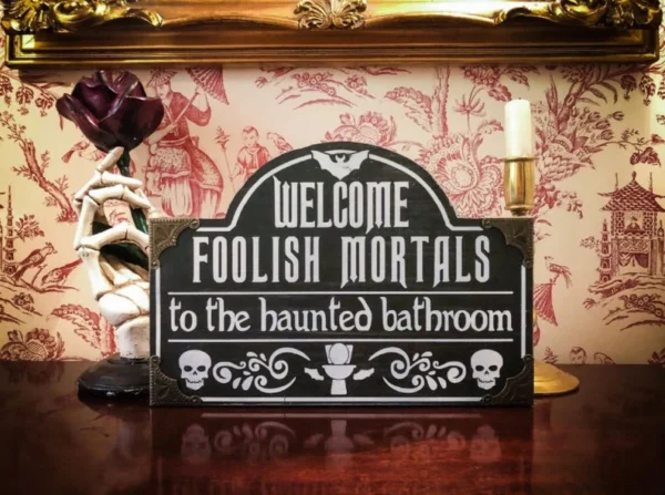 A sign that says welcome foolish mortals to the haunted bathroom.