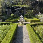 Formal garden with fountain and hedges.