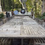 Long weathered wood patio table outdoors.