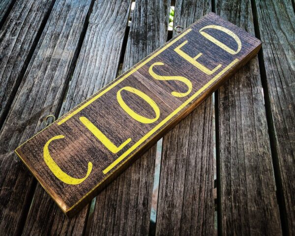 Wooden Closed sign on table.