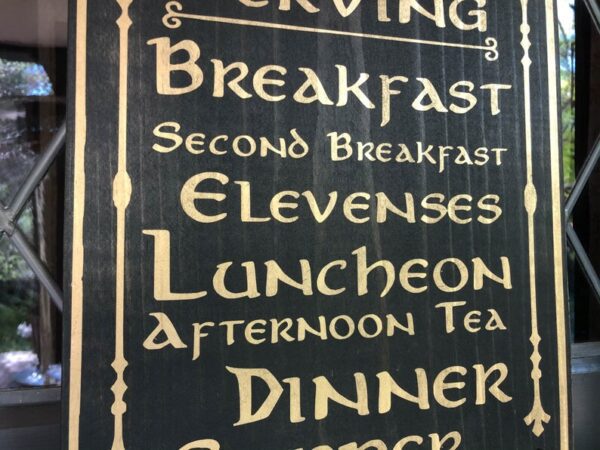 Here's an alt tag for the image: Medieval-style meal times sign.