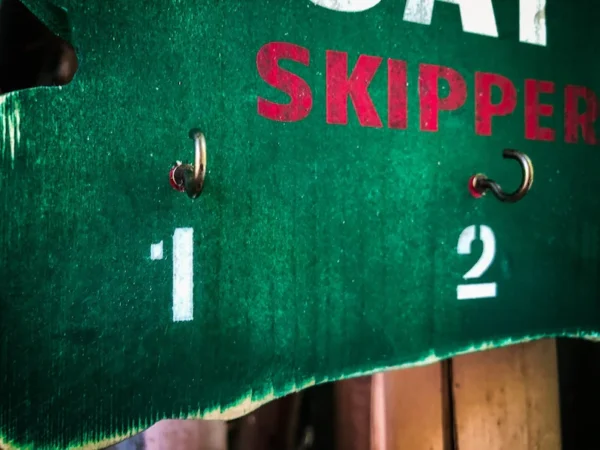 Green Skipper sign with hooks and numbers.