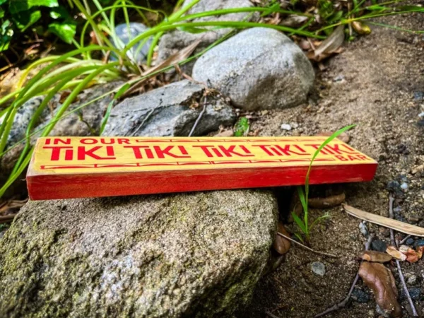 Tiki bar sign on rocks outdoors.