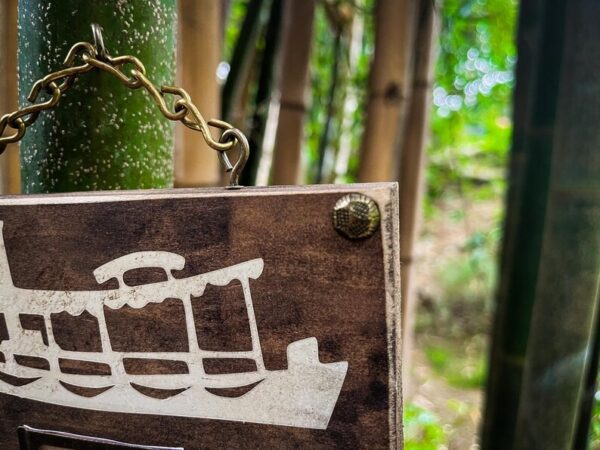 Wooden boat sign hanging in bamboo.