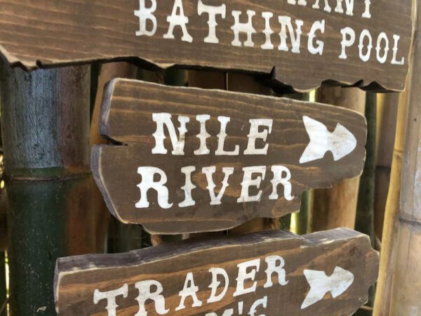 Wooden signs: Nile River, bathing pool, trader.