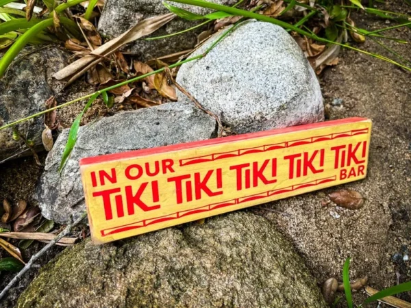 Tiki bar sign on rocks outdoors.