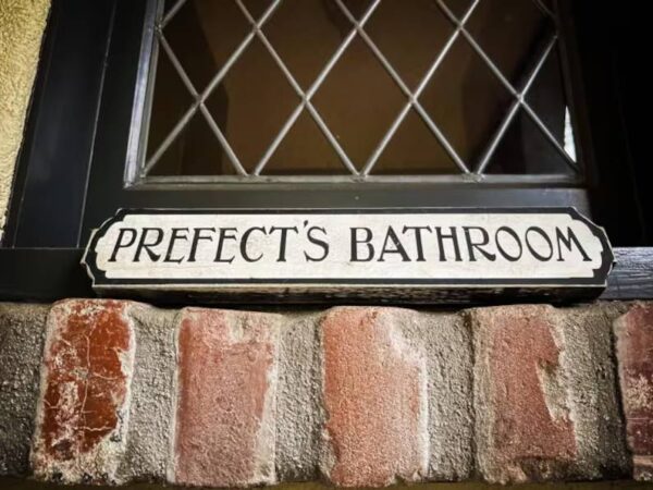 Prefect's bathroom sign on brick wall.