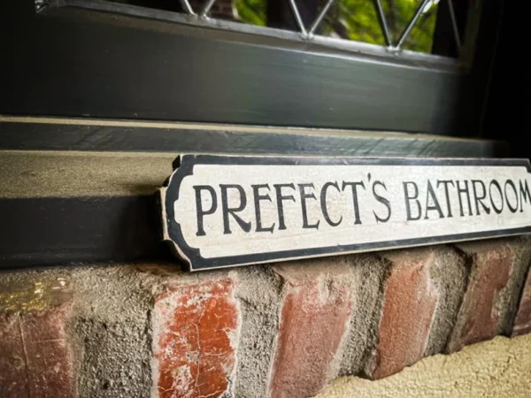 Prefect's bathroom sign on brick.