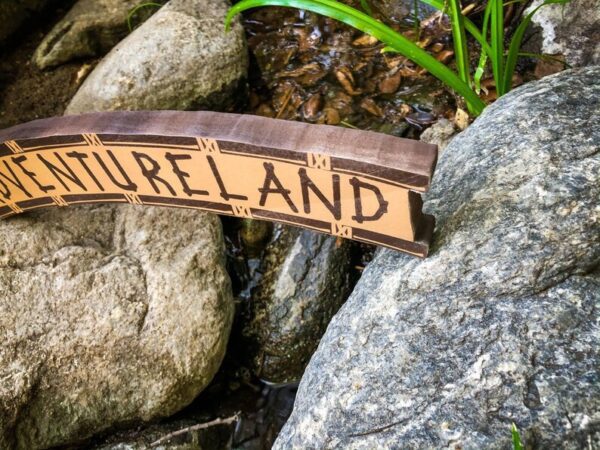 Adventureland sign by a stream.