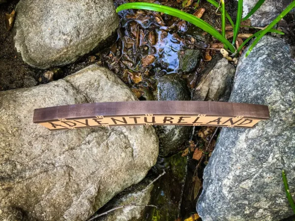 Adventureland sign by a stream.