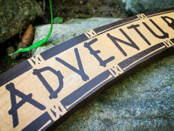 Wooden sign: Adventure awaits.