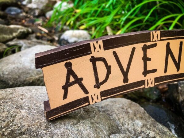 Wooden sign: Adventure awaits.