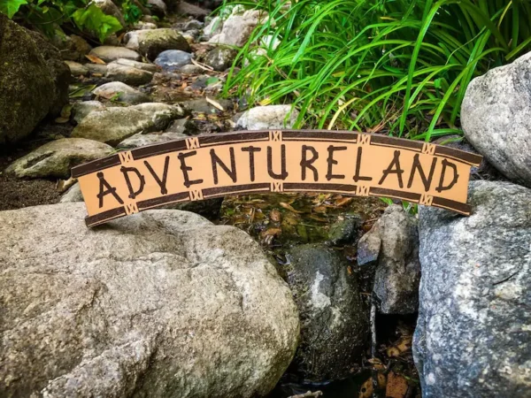 Adventureland sign by a stream.