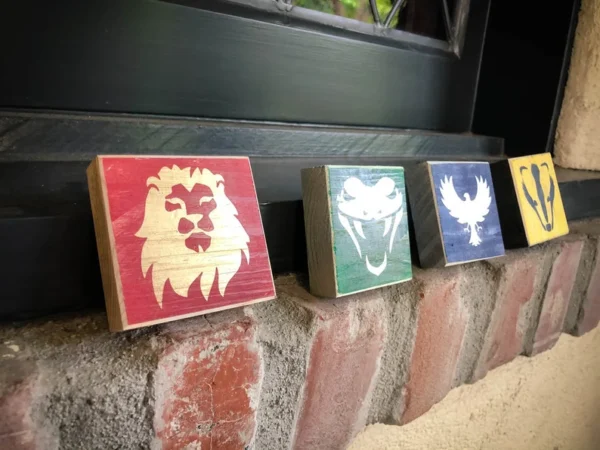 Here's an alt tag for the image: Four Hogwarts house crests on wood.