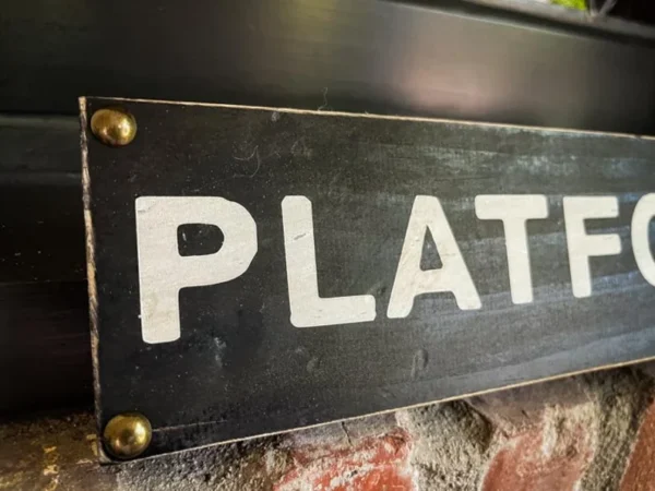 Black platform sign with brass studs.