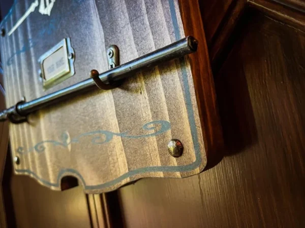 Wooden wall-mounted coat hook with label.