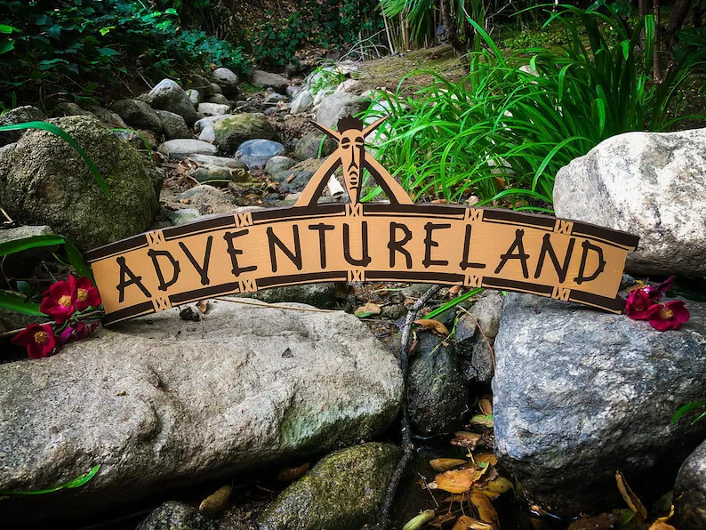 Adventureland sign by rocks and stream.