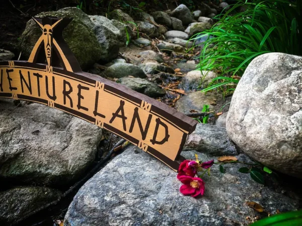 Adventureland sign by rocks and flowers