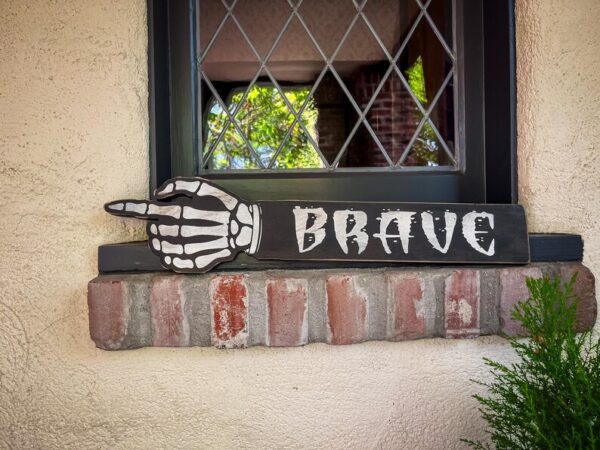 Skeleton hand points to: Be brave.