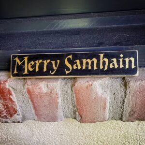 Sign reading "Merry Samhain" on brick wall.